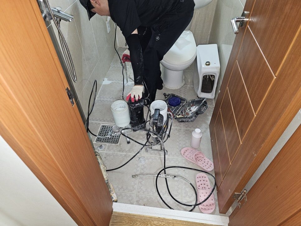 화장실 바닥에 주입 장비와 호스를 설치해 비파괴 주입식 방수를 시공하는 모습